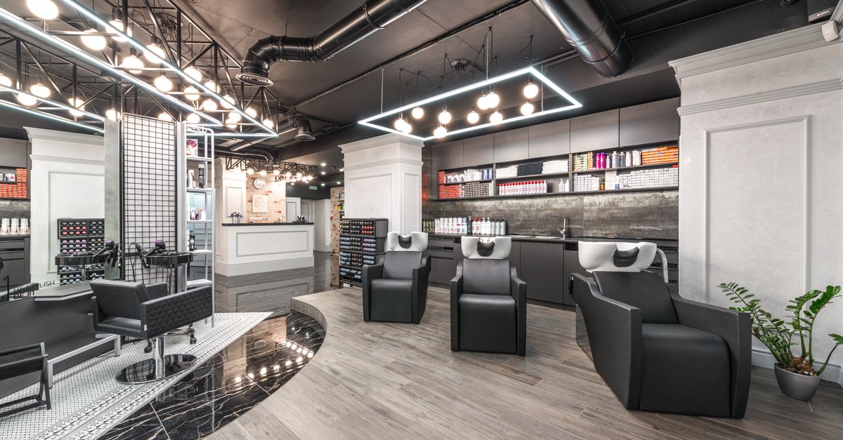 The interior of a modern beauty salon with styling chairs, mirrored stations and product shelving