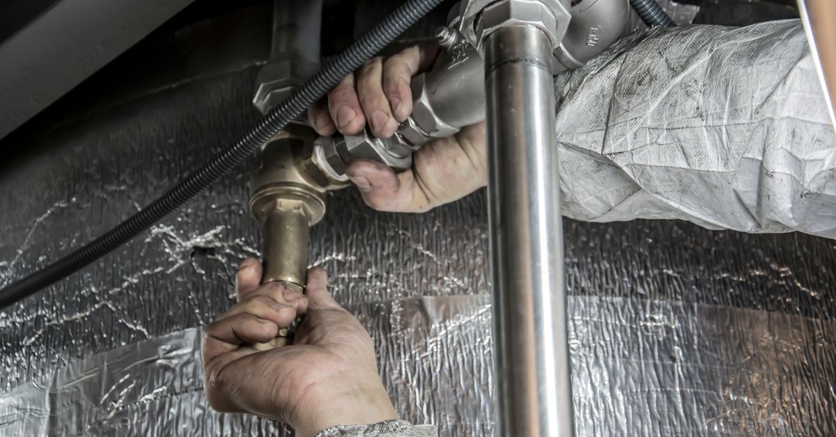 A plumber tightening a fitting on residential copper supply pipe